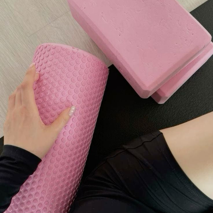 Person using pink foam rollers on a yoga mat